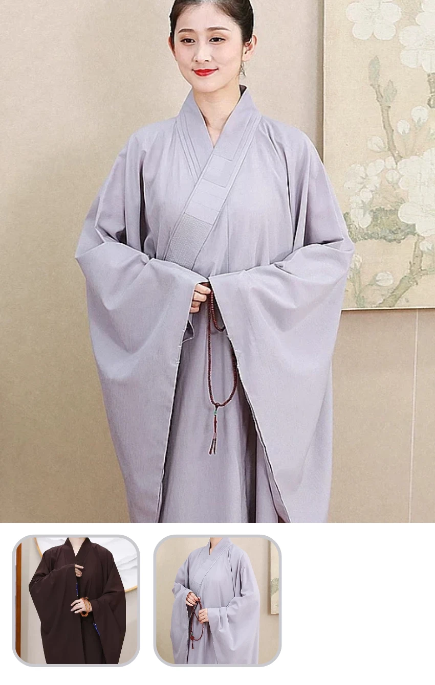 Person wearing a light gray traditional robe with wide sleeves, hands clasped, holding a beaded mala necklace indoors release.